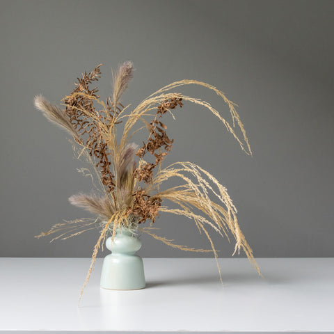 Timeless neutral dried arrangement in a cool blue ceramic bud vase