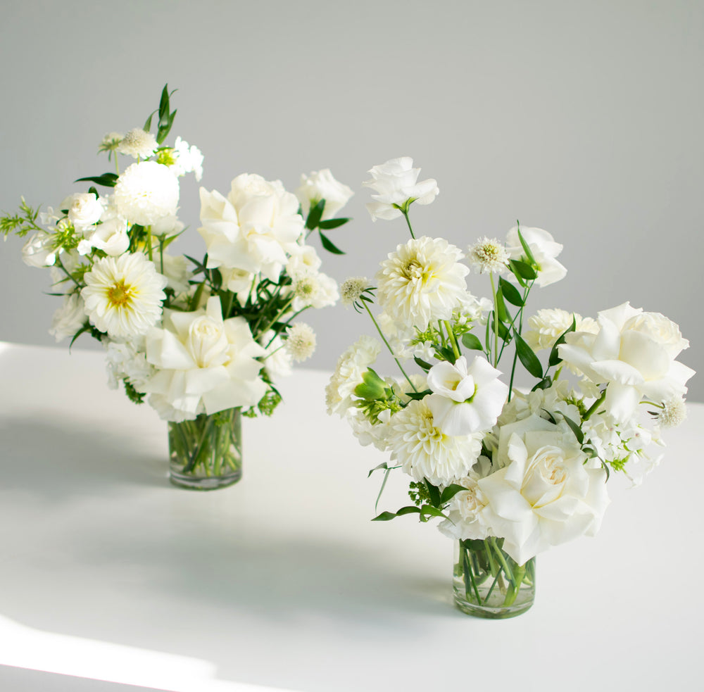 Two minimalist wedding arrangements full of large white blooms.