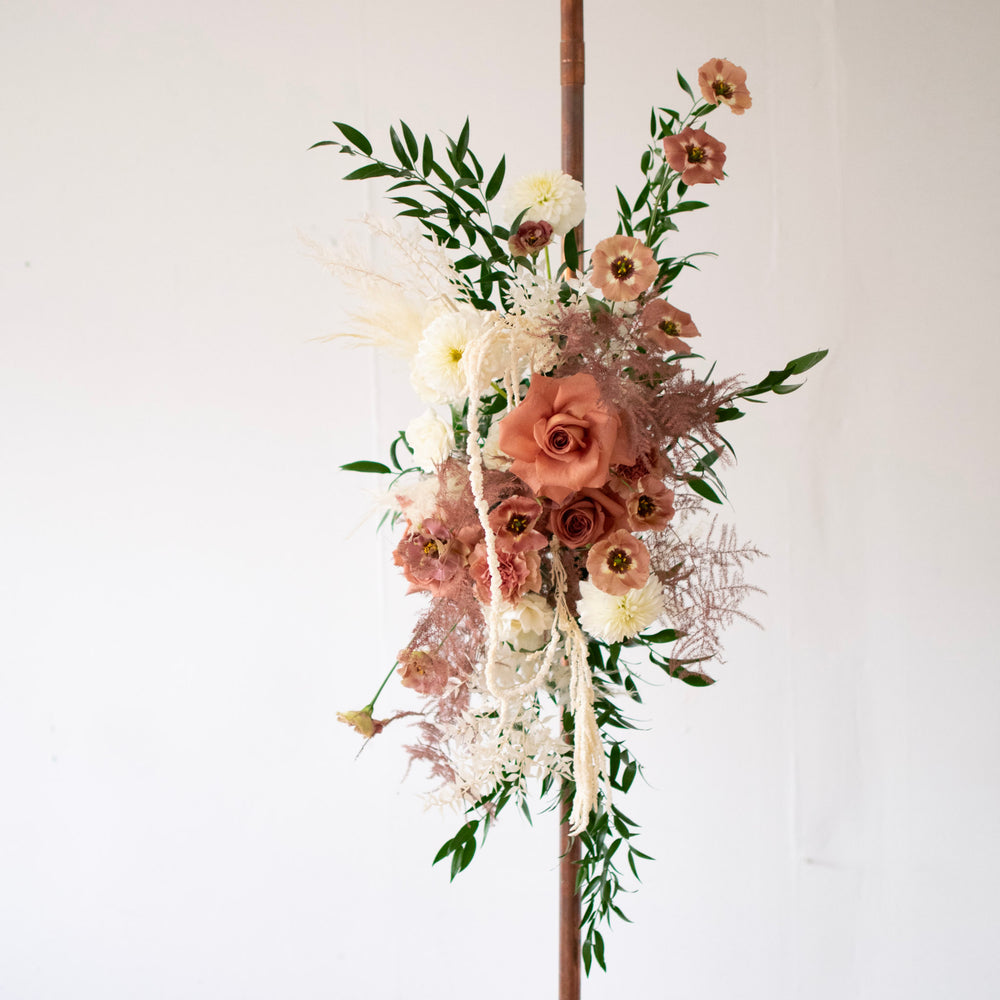 A small floral piece fastened to a simple copper arch.