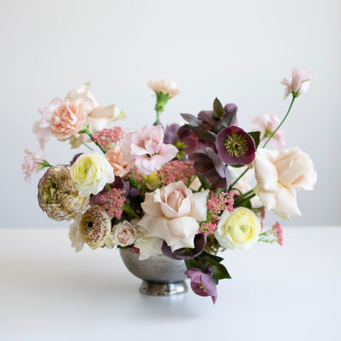 elegant arrangement with peaches, yellows, light pinks and pops of purple.