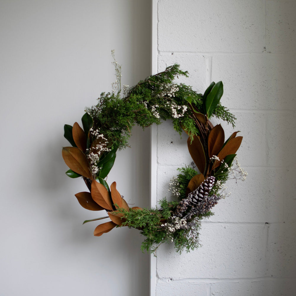 Winter greens, pinecone and magnolia leaves in a wreath