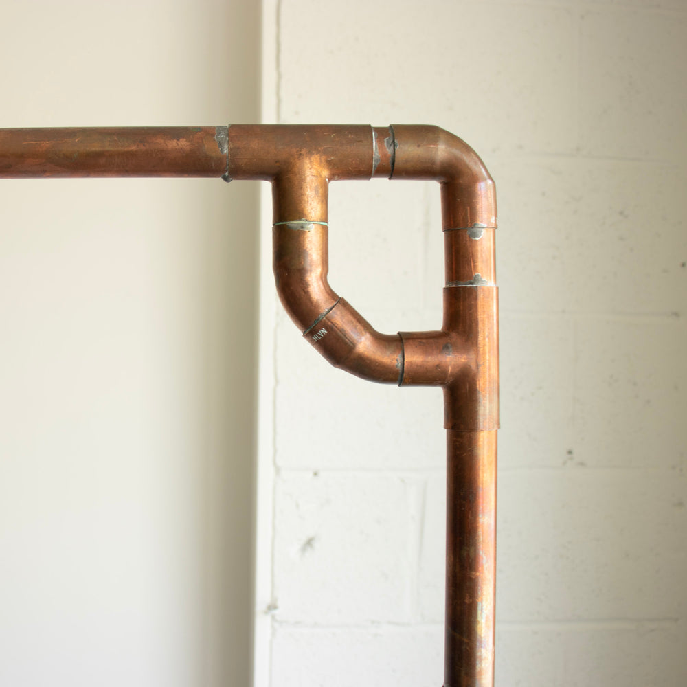 A close-up of the corner of a copper arch. The construction is rustic and industrial.