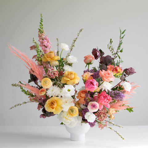 a gorgeous array of spring colors, soft pinks, peaches, yellows, and purples in a large flower arrangement
