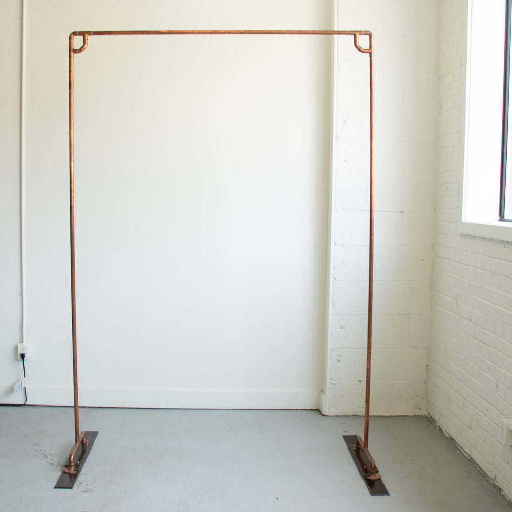 A simple copper arch against a plain white wall.