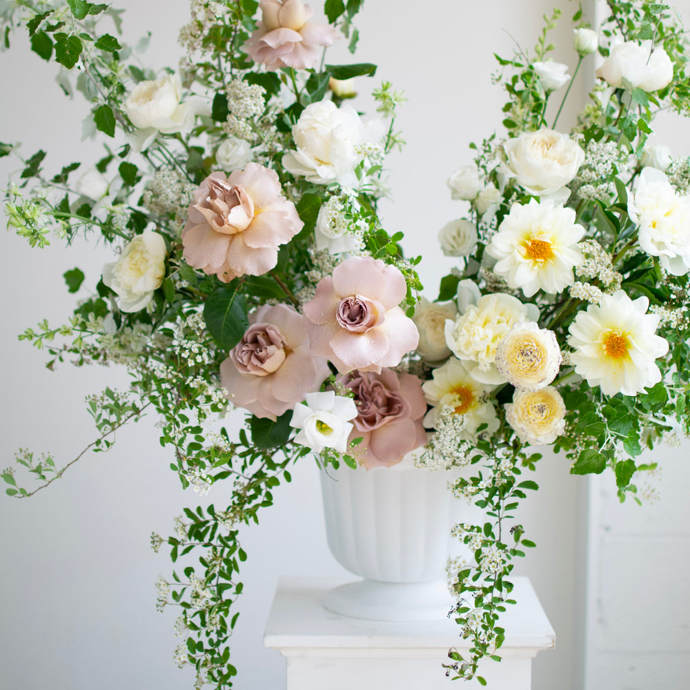 A close up of the flowers included in a white and dusty rose sympathy arrangement.