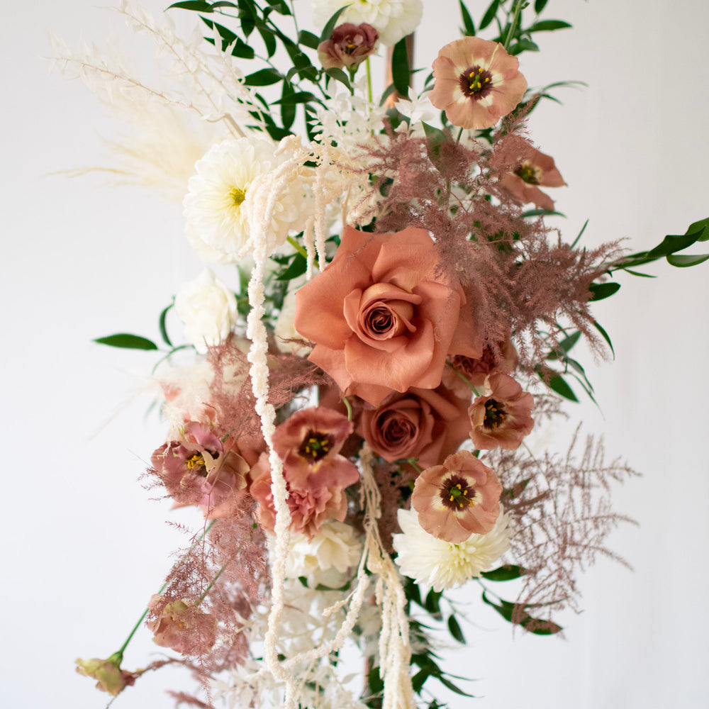 A close-up of a rose. Dark blush flowers and white trailing flowers surround it.