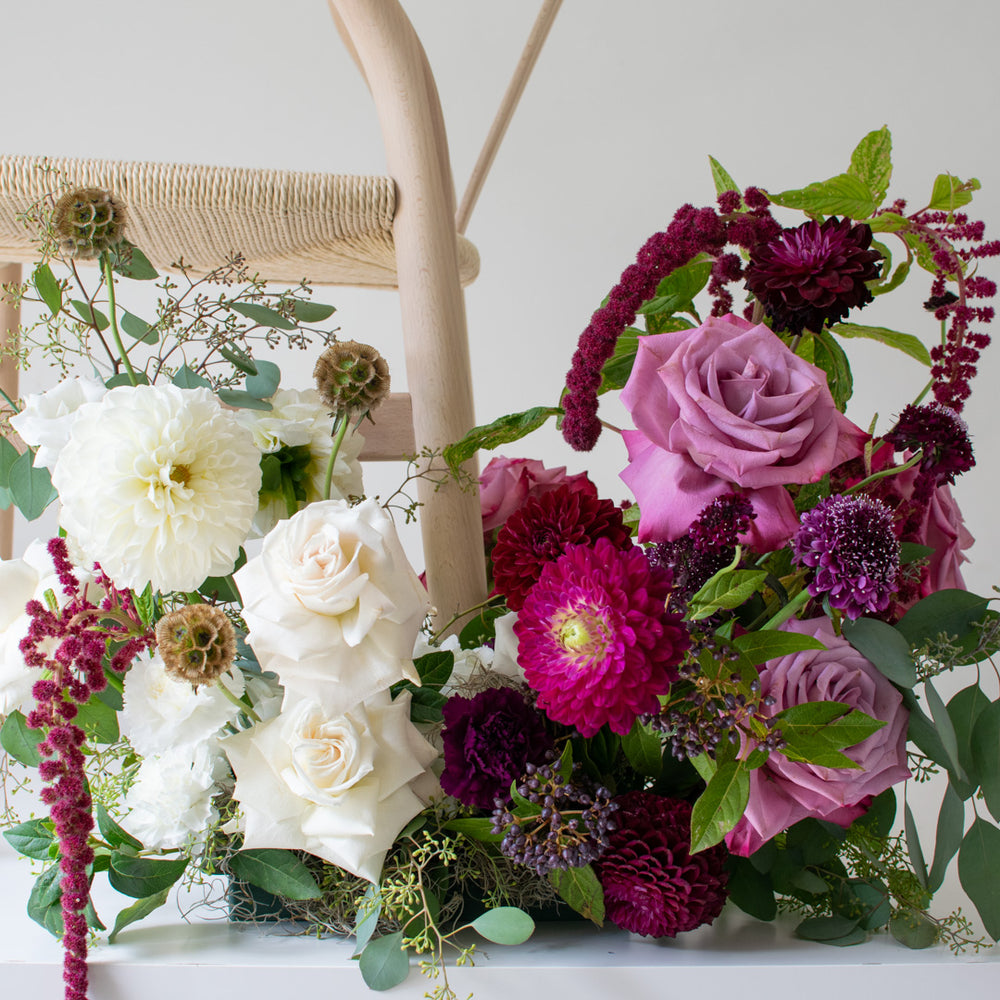 A close shot of purple and white flowers, among which are many roses.