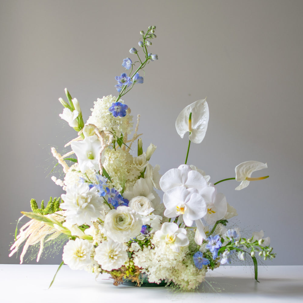 A large white floral arrangement for weddings with blue accents.