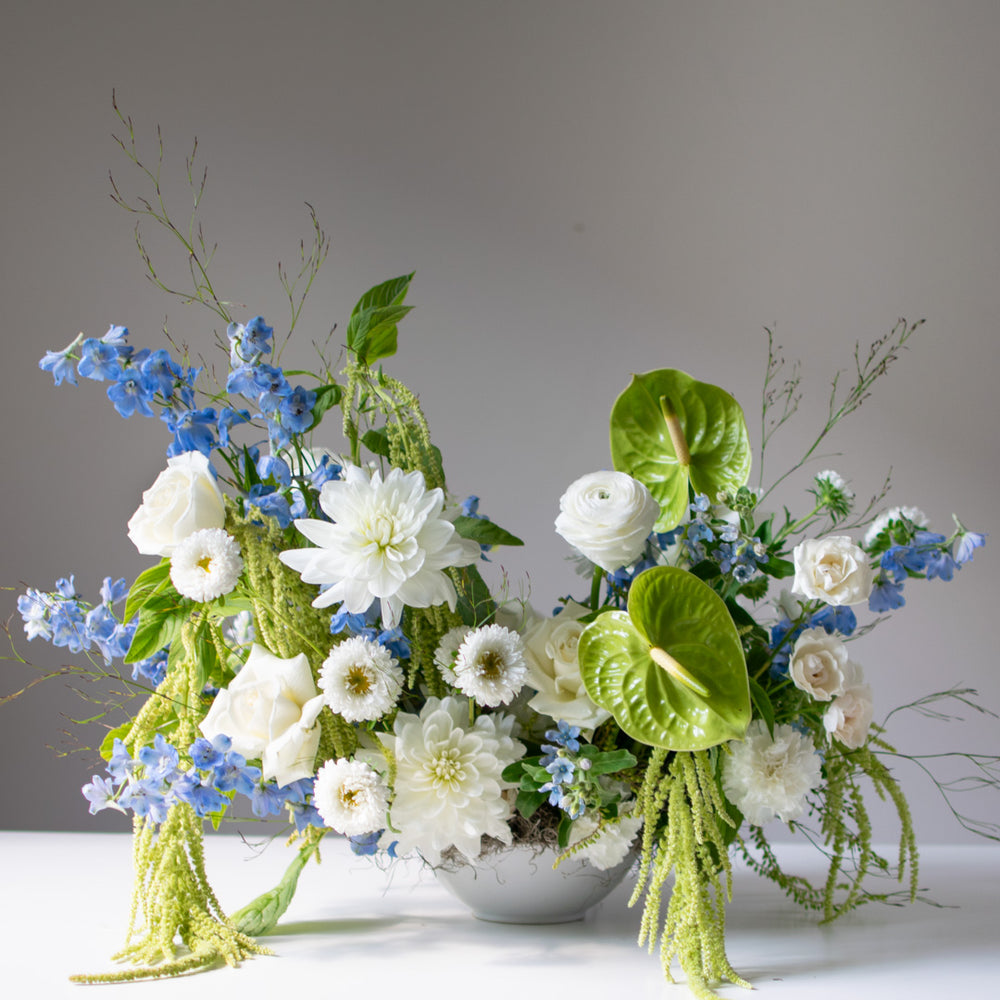 A floral arrangement with many large blooms in white, blue, and green.