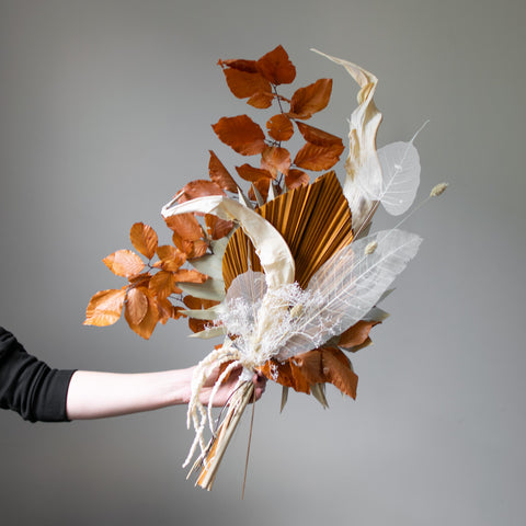 A dried, autumn style bouquet with white skeleton leaves.
