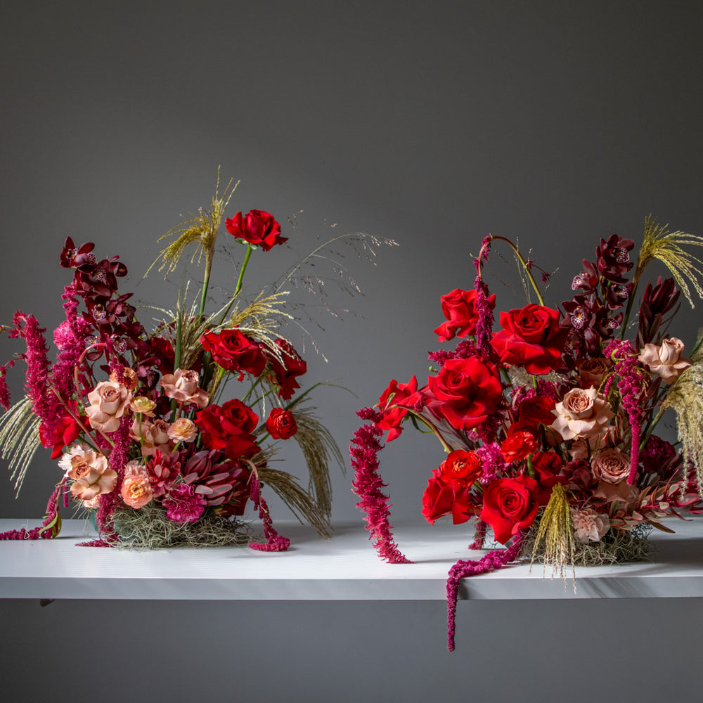Two large red floral arrangement for weddings side by side with neutral accents.