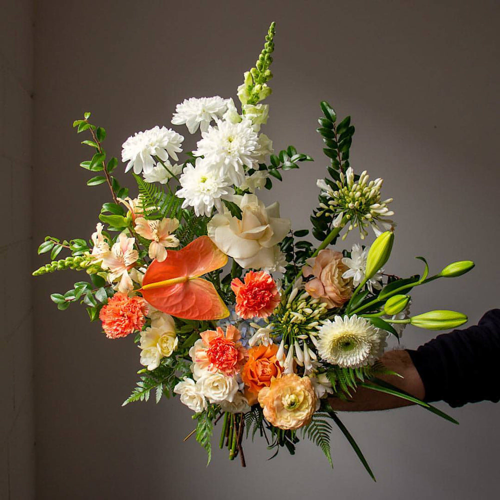 A white and green floral bouquet with pops of warm pink flowers.