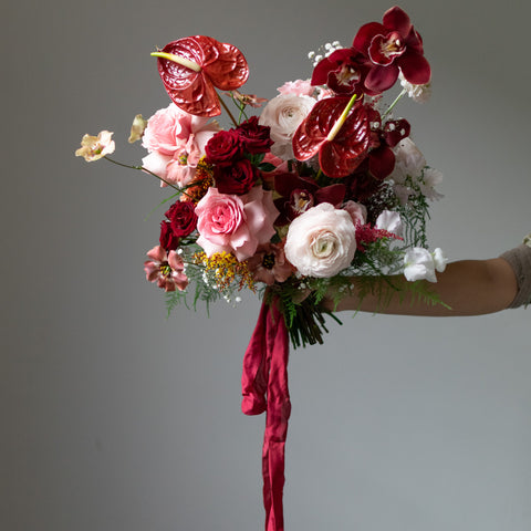 A bridal bouquet made with many deep red anthuriums and tied with red silk.