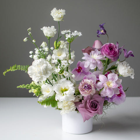 A split palette floral arrangement with whites and soft purple tones.