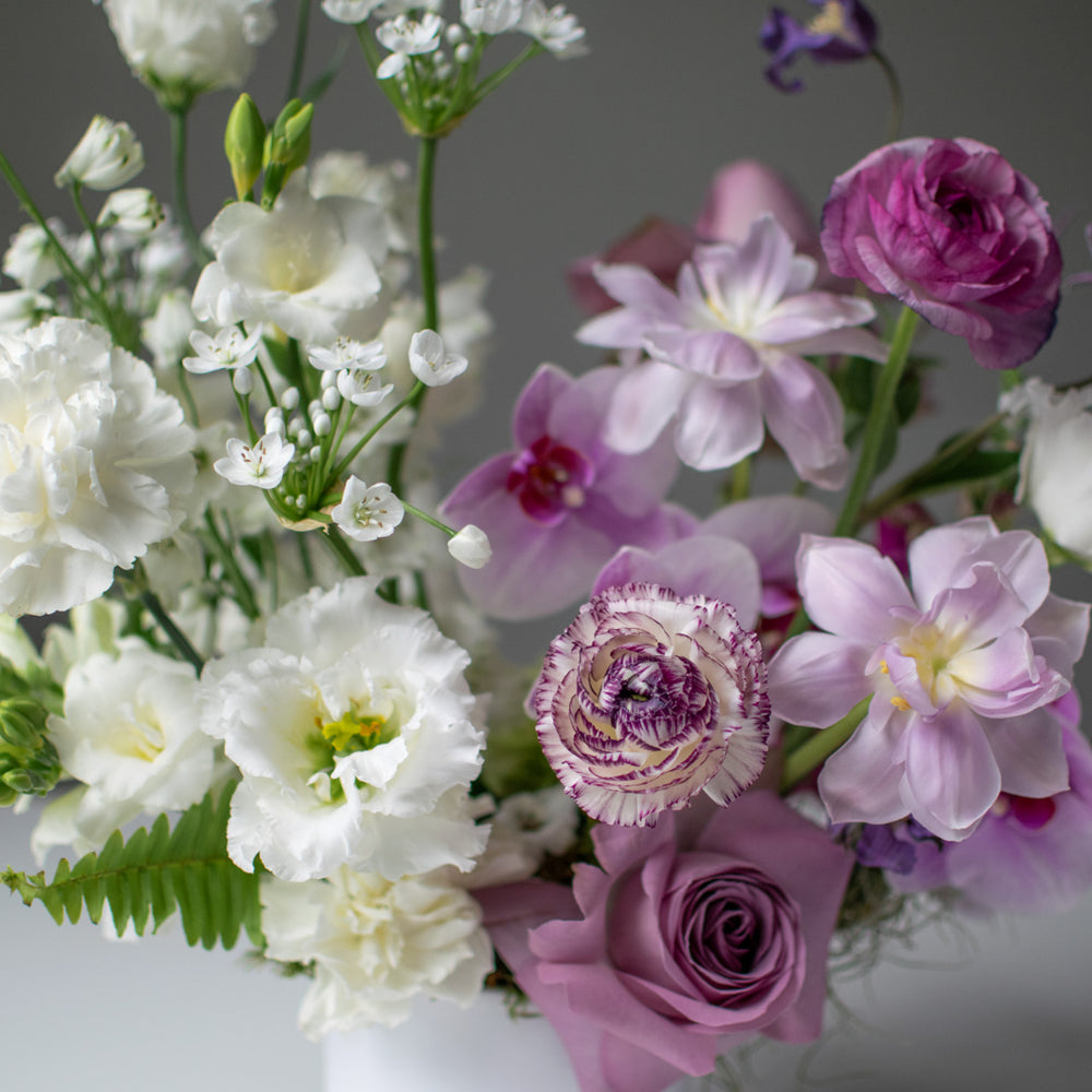 A close up  of white and purple fresh flowers in a bouquet.