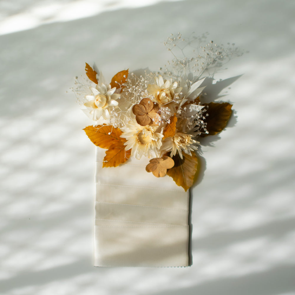 A neutral toned picket boutonniere made with dried white florals.