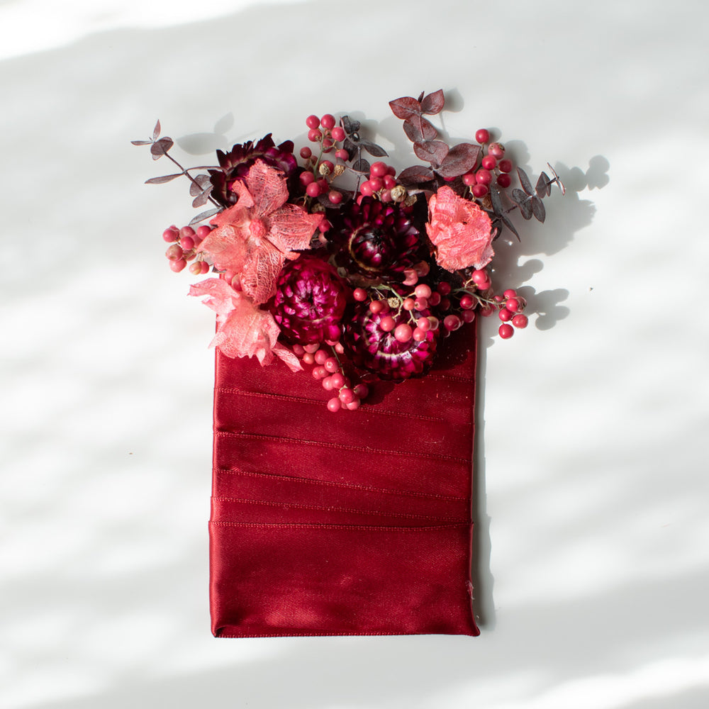 A pocket boutonniere made in a deep pink and red palette with eucalyptus and berries.