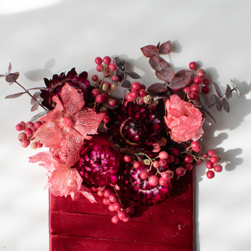 A close-up of the fresh and dried elements used in a red boutonniere.