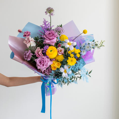 Bright purple and yellow flowers in a large hand-tied bouquet.