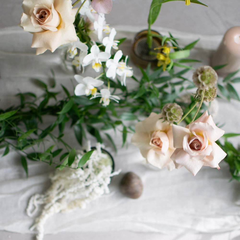 Cream coloured roses are in focus in the foreground, while a simple, fresh greenery garland is out of focus in the background.