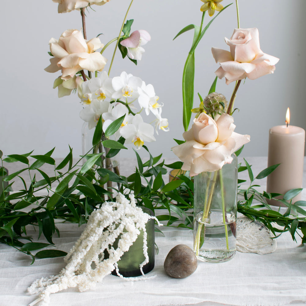 Light pink, reflexed roses and white orchids compliment the simple greenery on this white tablescape.