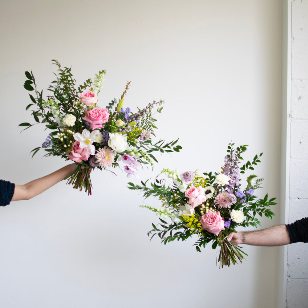 Two differently sized bouquets are held out against a white background.