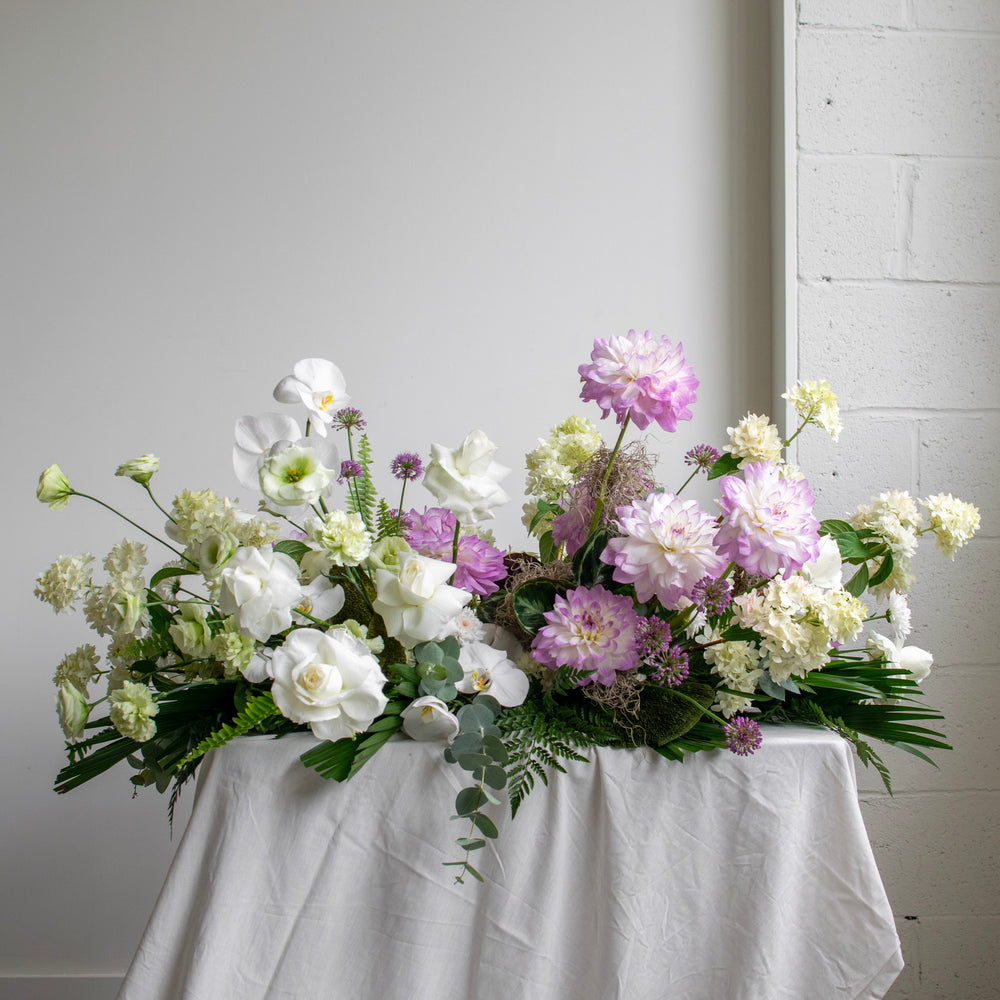 A two-toned casket spray, with white flowers on the left side, and soft purple blooms on the right.