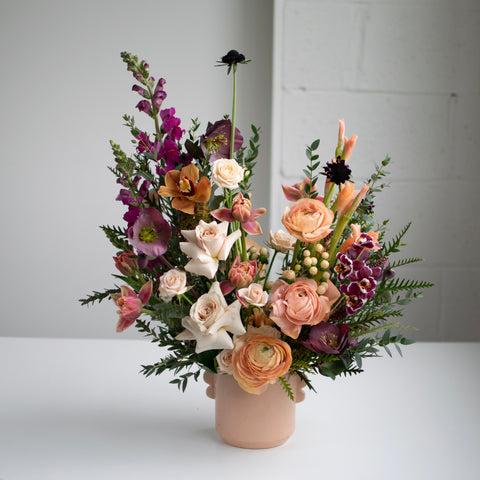 A moody flower arrangement made with neutral pinks, peaches, and blush roses.