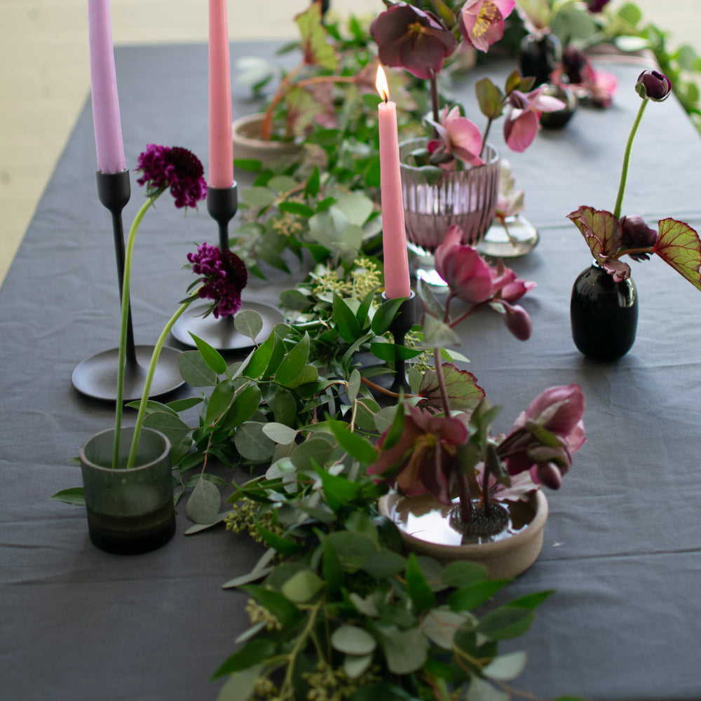 A floral tablescape with luscious greenery table runners and muted pink flowers.