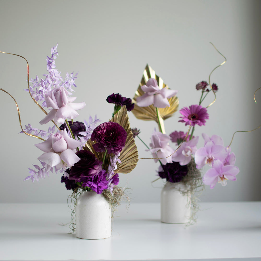 Two bud arrangements with purple color palettes and gold accents.