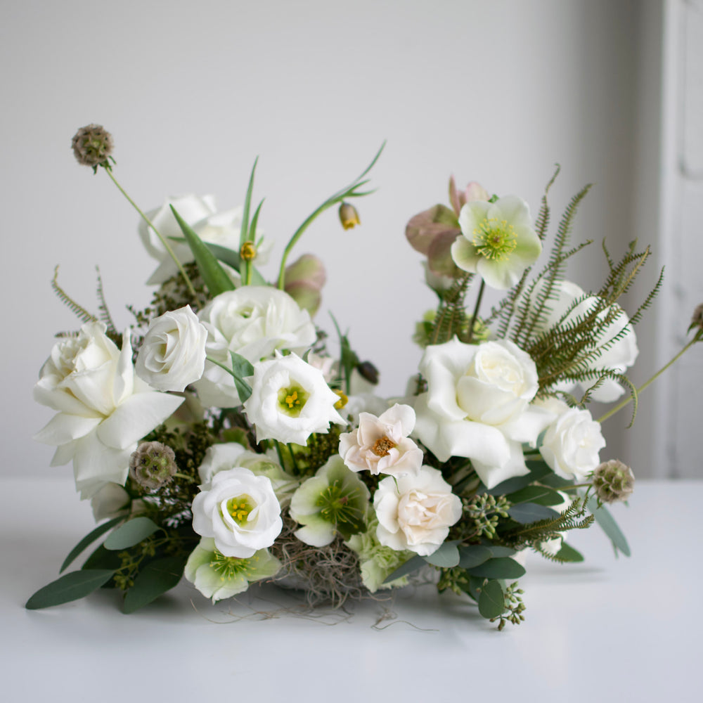 A fresh, white and green floral centerpiece in a hidden white vase.