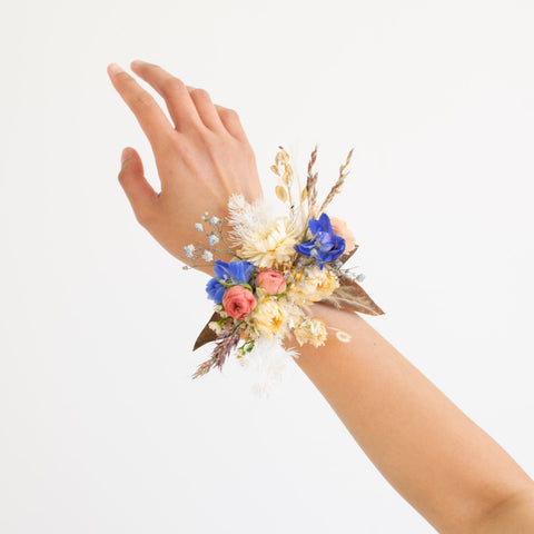 A dried corsage with pops of pink and blue fresh flowers.