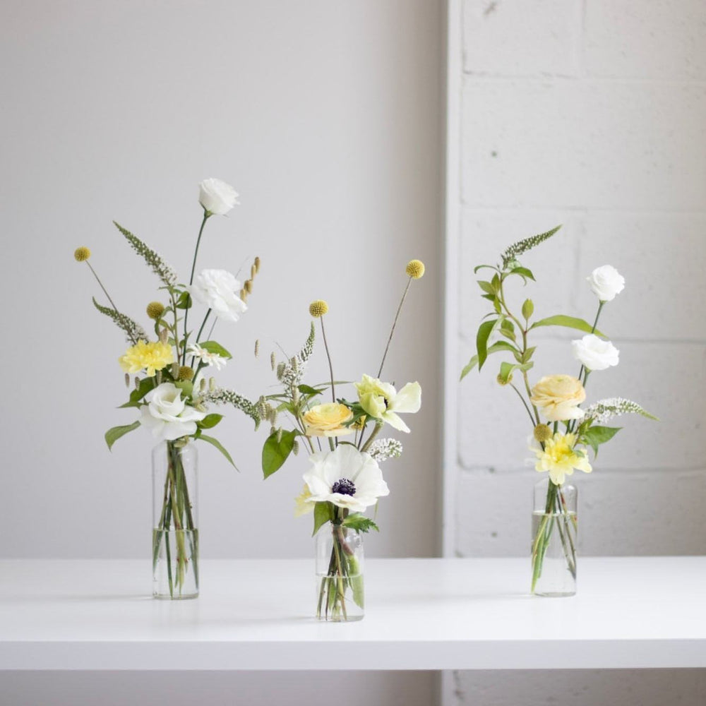 Simple and elegant flowers are arranged in straight sided bud vases.