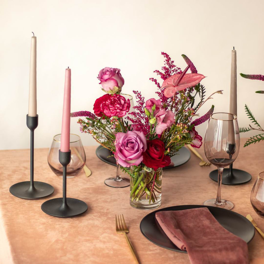 A small floral centrepiece complements a dusty rose tablescape with tapered candles.