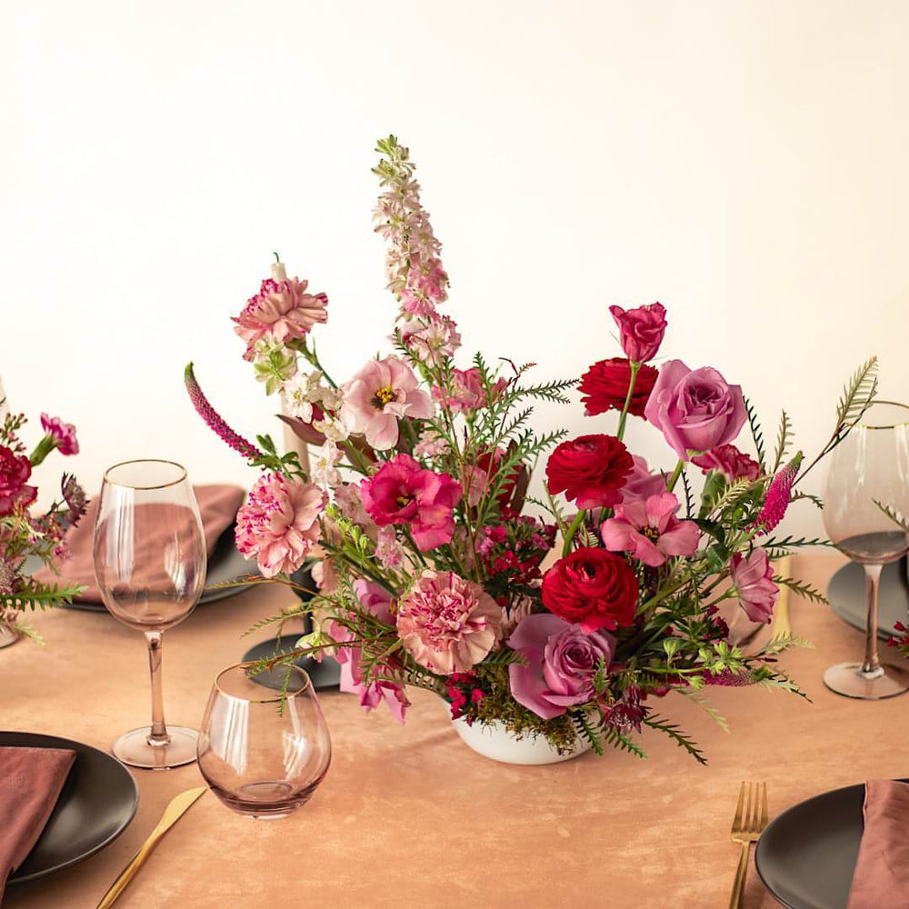 A pink and red fresh flower arrangement for events with roses and carnations.