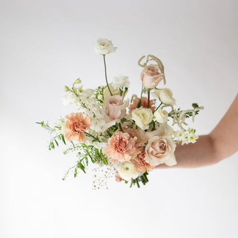 A small, bridesmaid sized bouquet in soft creams and pinks.