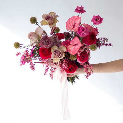 A romantic bridal bouquet, made up of deep reds and light pinks with a trailing silk ribbon.