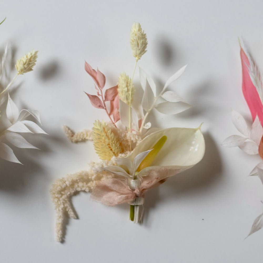 A white and pink boutonniere with a large white anthurium and cream coloured trailing flowers.