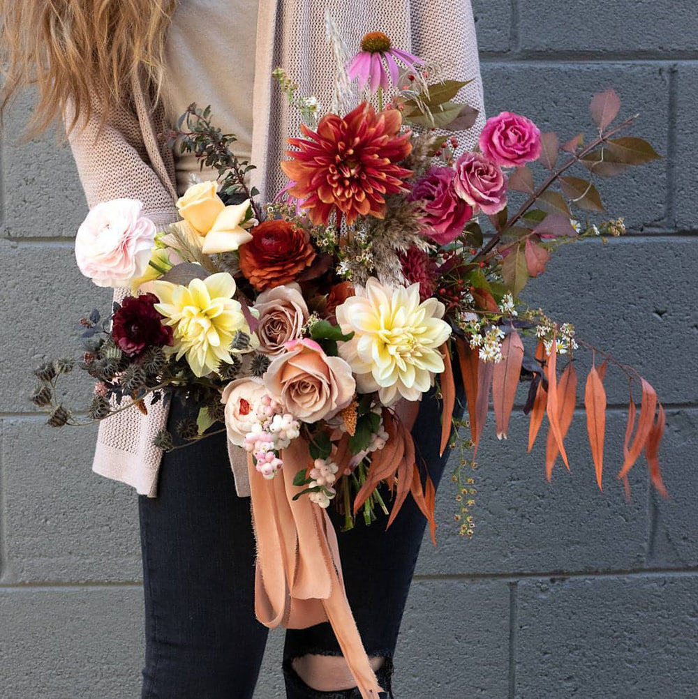 An autumn themed wedding bouquet with deep reds and dark greenery.