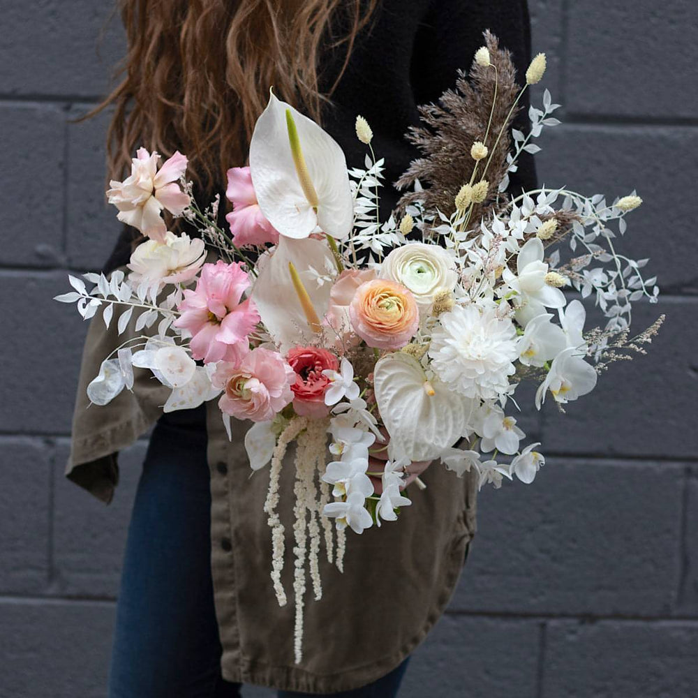 A white and light pink bouquet made with bunny tails and trailing flowers.