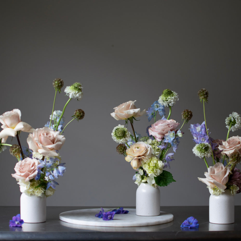 Three bud arrangements in cream vases. Soft pink roses are used in all arrangements.