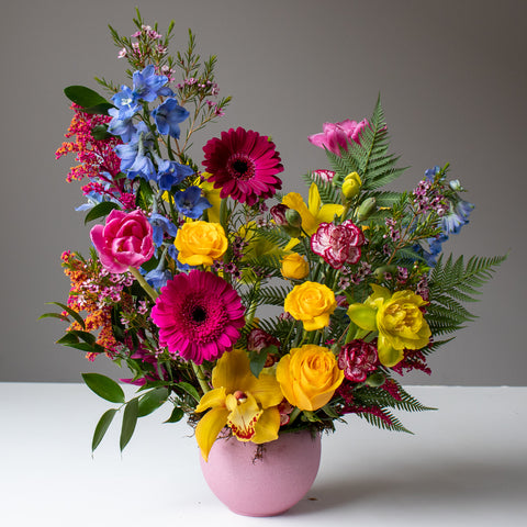 A bouquet of fresh colourful flowers in a pink vase.