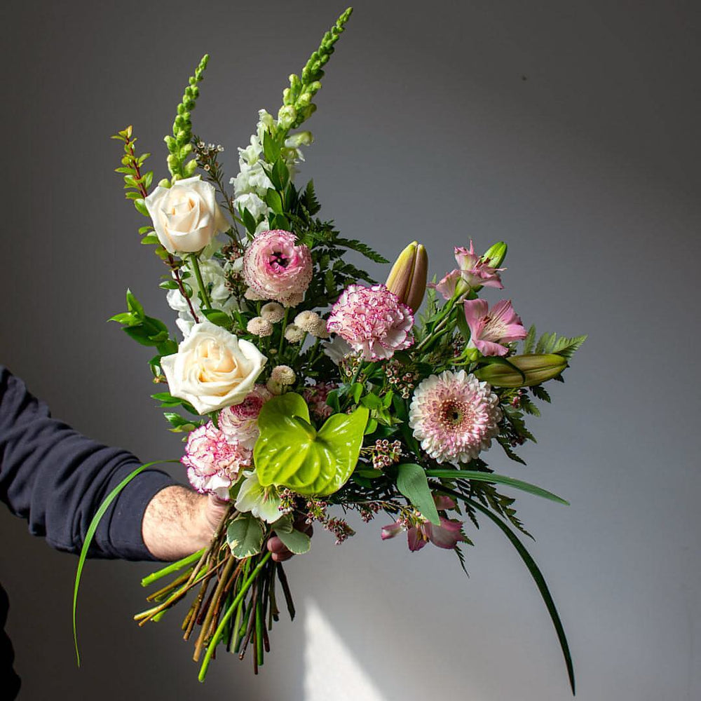 A soft white and pink flowers create a subtly beautiful hand held bouquet.
