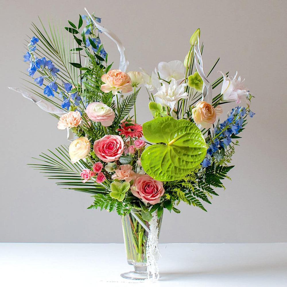 A bright, tropical looking fresh floral bouquet in a glass vase.