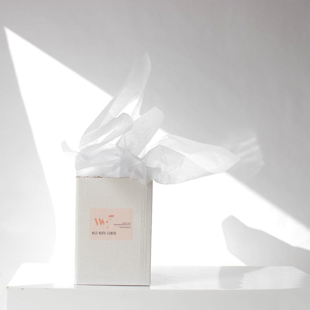 Sustainable cardboard packaging for flower bouquets on a white table.